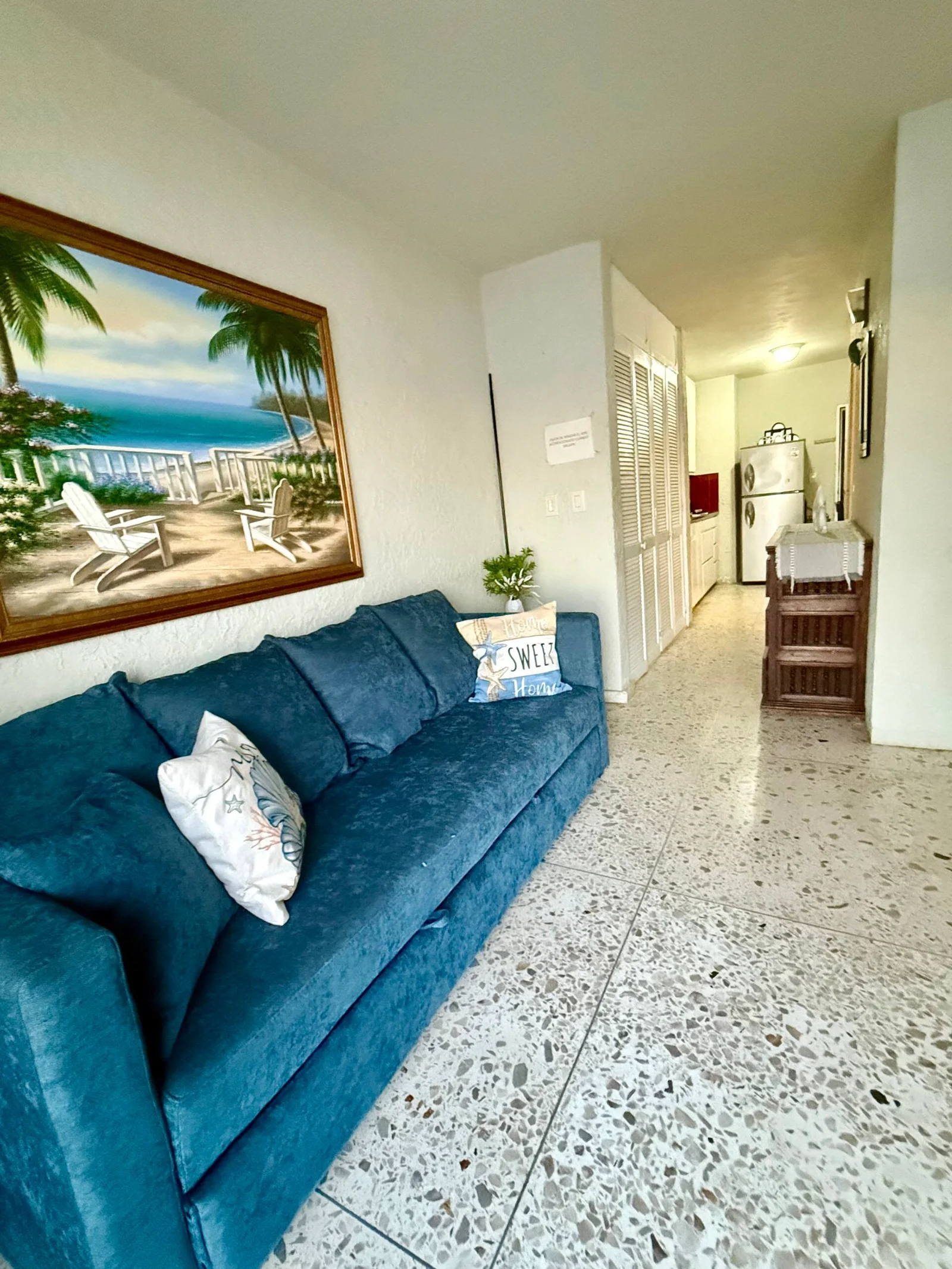 Sala con sofá azul y cuadro de la playa