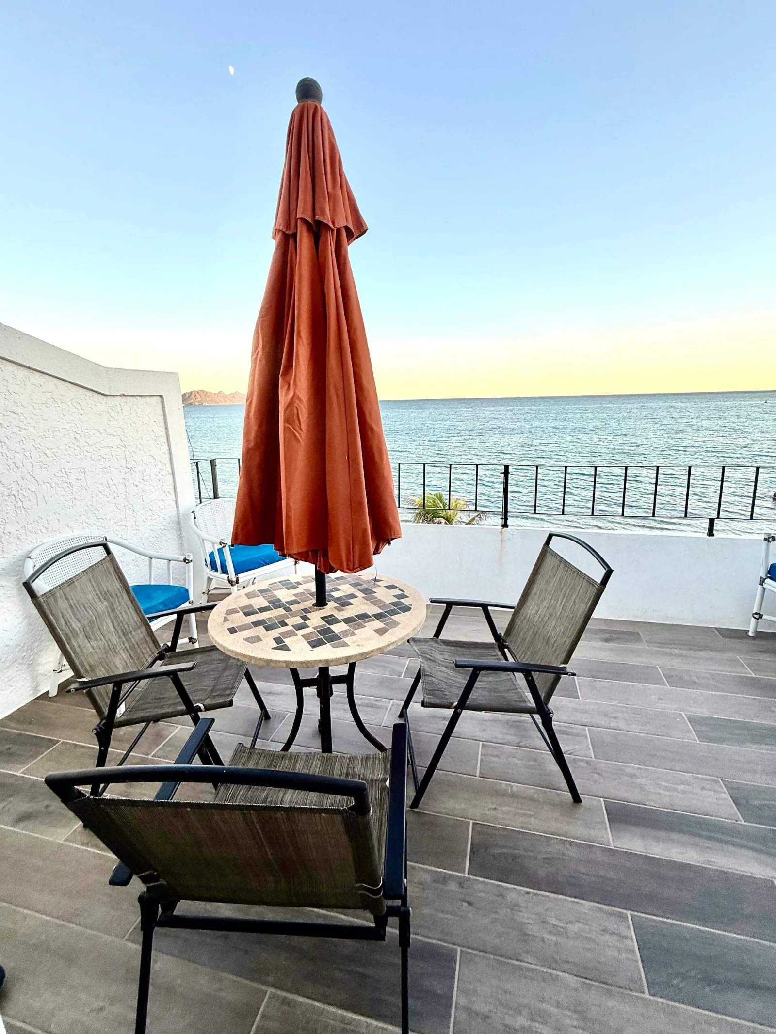 Terraza con sombrilla y mesa frente al mar